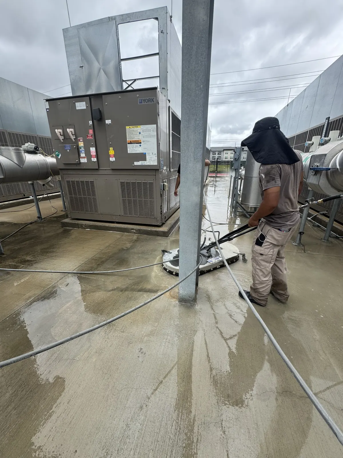 Technician using a commercial surface cleaner on concrete at a Houston facility